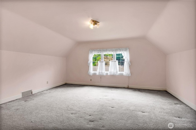additional living space with baseboards, vaulted ceiling, carpet flooring, and visible vents