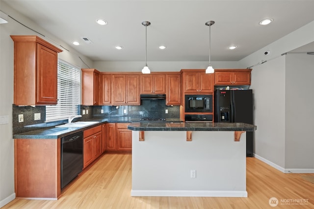 kitchen with a kitchen breakfast bar, a sink, ventilation hood, black appliances, and light wood-style flooring