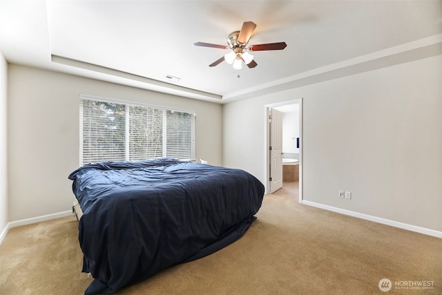 bedroom featuring visible vents, baseboards, a raised ceiling, ensuite bathroom, and light carpet