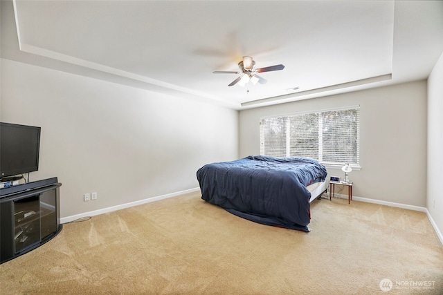 carpeted bedroom with baseboards, a ceiling fan, and a tray ceiling