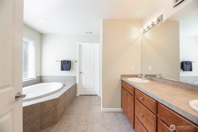 bathroom featuring double vanity, a bath, visible vents, a sink, and tile patterned floors