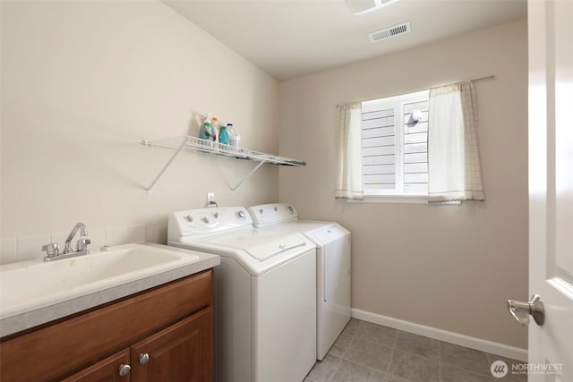 clothes washing area with cabinet space, a sink, baseboards, visible vents, and washer and clothes dryer