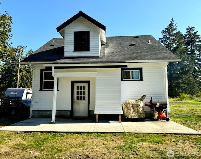 back of property with a patio, a yard, and roof with shingles