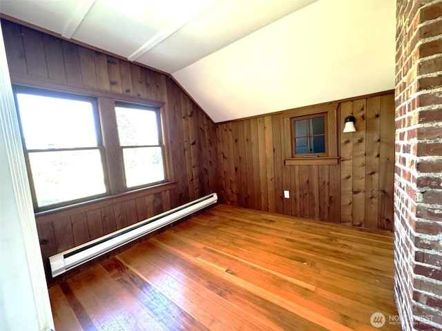 bonus room with a baseboard radiator, hardwood / wood-style flooring, vaulted ceiling, and wood walls