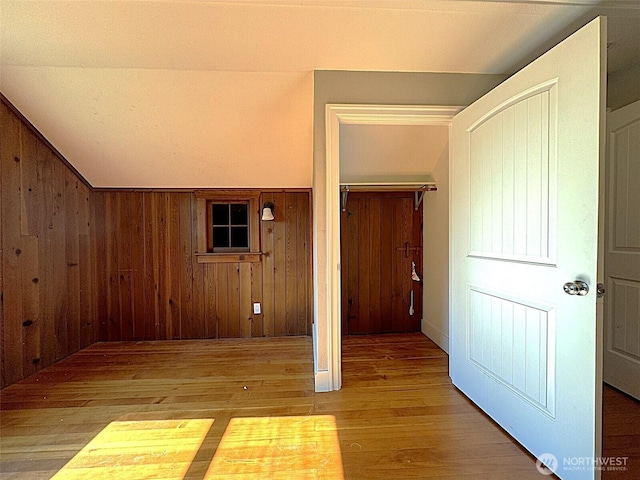 hall featuring wood finished floors, lofted ceiling, and wood walls