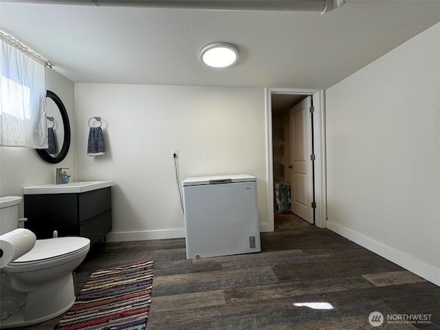 bathroom with toilet, baseboards, wood finished floors, and vanity