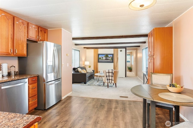 3832 164th St SW Unit 10, Lynnwood, WA 98087 - kitchen featuring wood finished floors, beam ceiling, open floor plan, brown cabinets, and stainless steel appliances