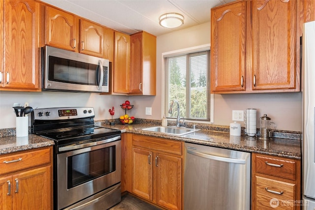 3832 164th St SW Unit 10, Lynnwood, WA 98087 - kitchen with brown cabinetry, a sink, dark stone counters, and appliances with stainless steel finishes
