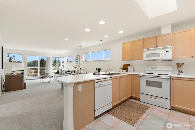 kitchen with white appliances, light brown cabinets, open floor plan, recessed lighting, and a sink