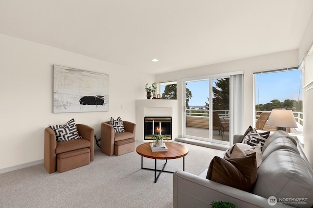 living area with a glass covered fireplace, carpet, recessed lighting, and baseboards