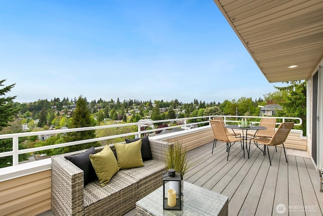 wooden deck with outdoor dining space and view of wooded area