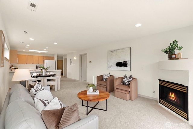 living room featuring light colored carpet, recessed lighting, a glass covered fireplace, and baseboards