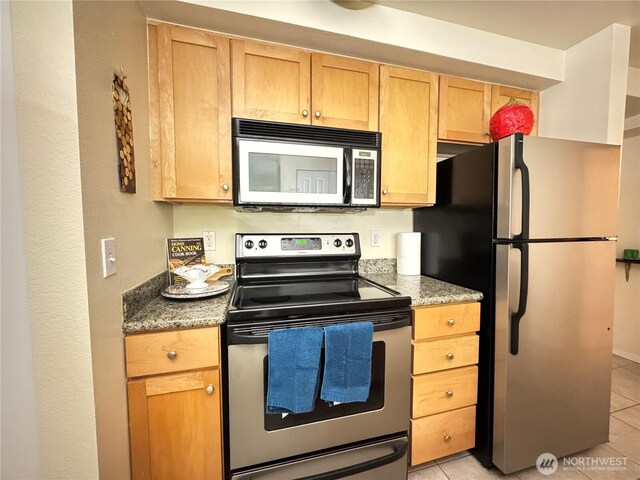 kitchen featuring light tile patterned floors, light stone countertops, and stainless steel appliances