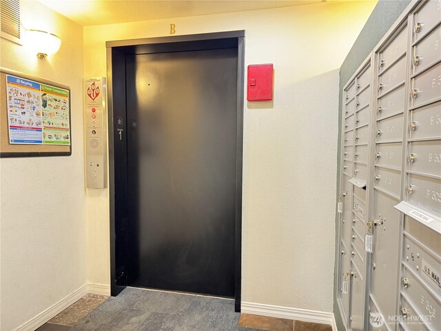 hall featuring baseboards, visible vents, elevator, and mail area