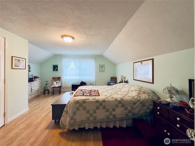 bedroom with a textured ceiling, baseboards, wood finished floors, and lofted ceiling