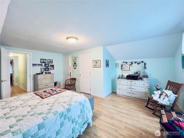 bedroom featuring a textured ceiling, baseboards, and light wood-type flooring