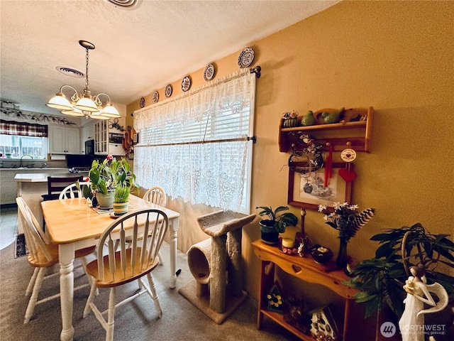 dining space featuring carpet floors, a textured ceiling, a notable chandelier, and visible vents