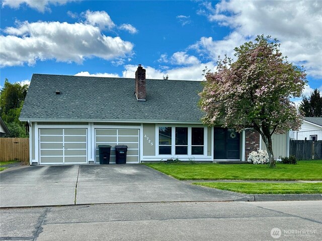 view of front of house featuring fence, a front yard, a chimney, and driveway