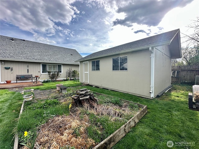 rear view of property with a vegetable garden, a yard, a deck, and fence