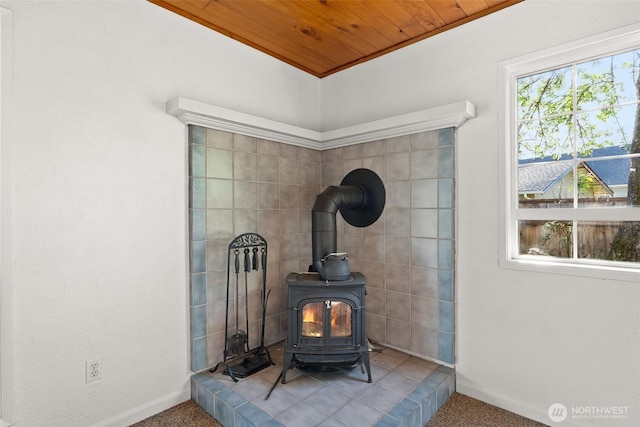 room details with carpet floors, baseboards, a wood stove, and wood ceiling