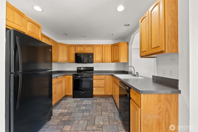 kitchen with dark countertops, stone finish floor, recessed lighting, a sink, and black appliances