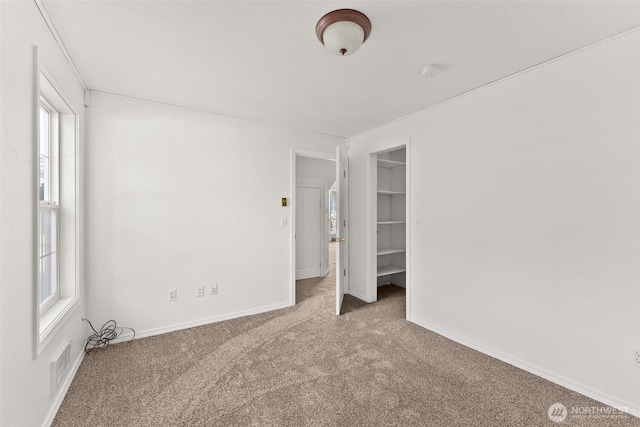 unfurnished bedroom featuring a walk in closet, multiple windows, carpet, and visible vents