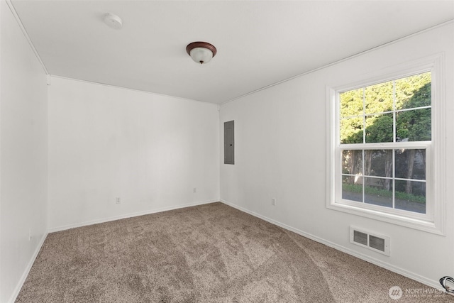carpeted spare room featuring visible vents, baseboards, and electric panel