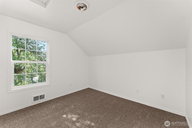 bonus room featuring visible vents, baseboards, dark carpet, and vaulted ceiling