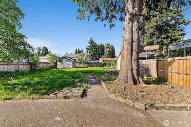 view of yard featuring a storage unit, a fenced backyard, and an outdoor structure