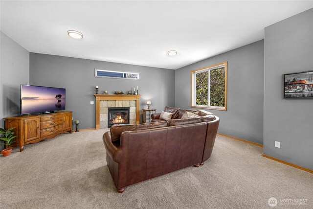 living area with baseboards, light colored carpet, and a tile fireplace