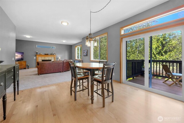 dining space with a chandelier, a tiled fireplace, and light wood-type flooring