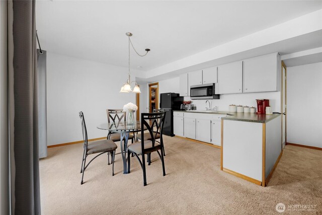 kitchen featuring white cabinetry, stainless steel microwave, light carpet, and dark countertops