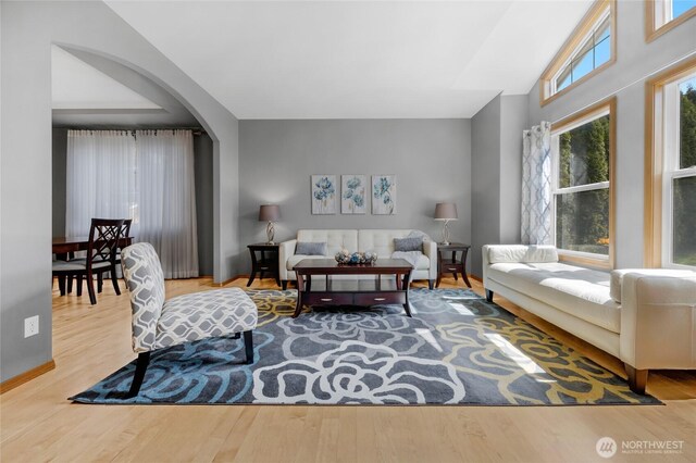 living area with arched walkways and wood finished floors