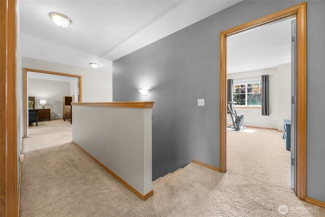 corridor with baseboards, carpet flooring, and an upstairs landing