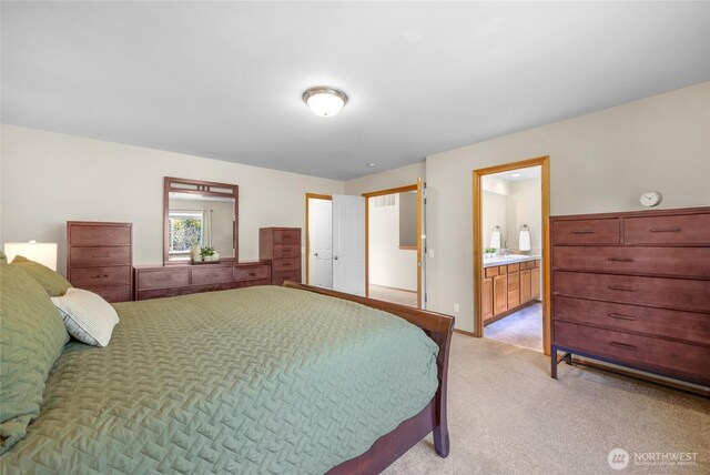 bedroom featuring light carpet and ensuite bathroom