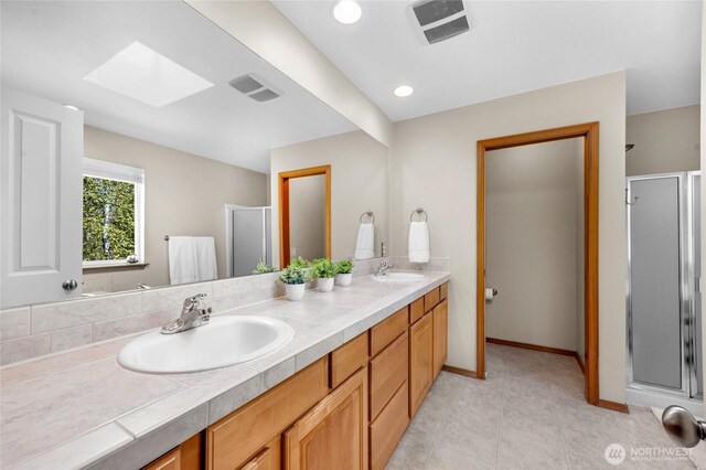 bathroom featuring visible vents, a sink, double vanity, and a skylight
