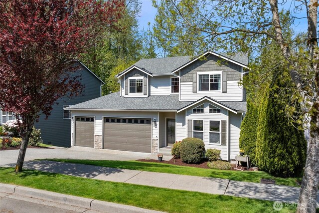 traditional-style home featuring driveway, roof with shingles, and a garage