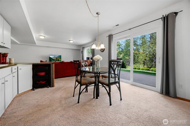 dining room with visible vents, a chandelier, and light colored carpet