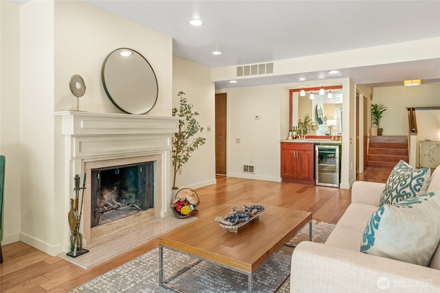 living area with visible vents, beverage cooler, recessed lighting, light wood-type flooring, and bar