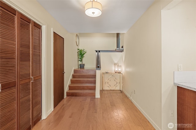 hallway with baseboards, light wood-style flooring, and stairway