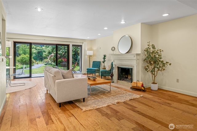 living area featuring recessed lighting, baseboards, a fireplace with flush hearth, and light wood finished floors