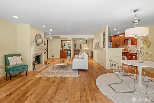 living area featuring visible vents, light wood-style flooring, baseboards, and a fireplace