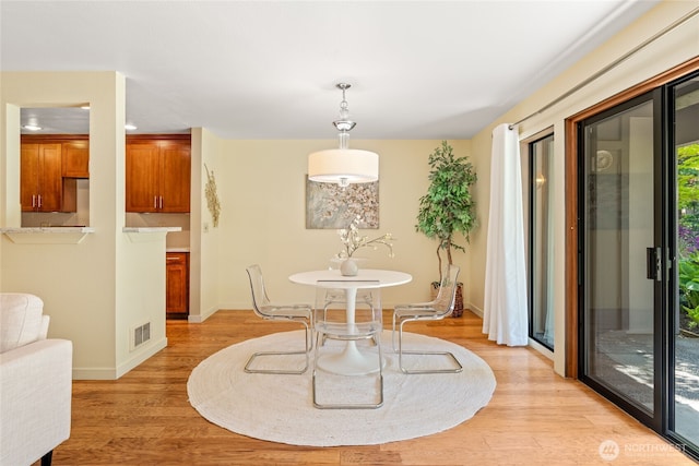 dining room with baseboards, visible vents, and light wood-style floors