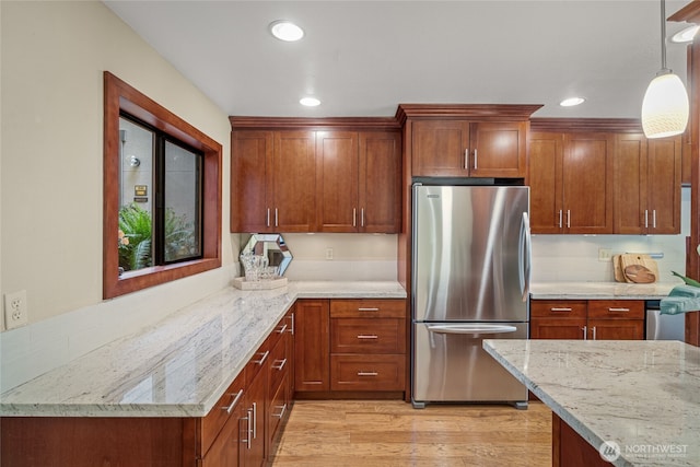 kitchen featuring pendant lighting, light stone counters, freestanding refrigerator, recessed lighting, and light wood-style flooring