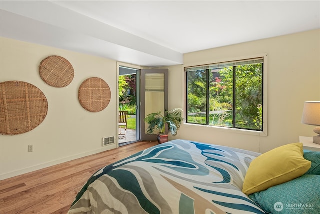 bedroom with access to outside, baseboards, visible vents, and wood finished floors