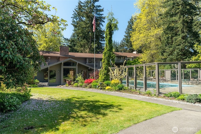 exterior space with a lawn, fence, a chimney, and an outdoor pool