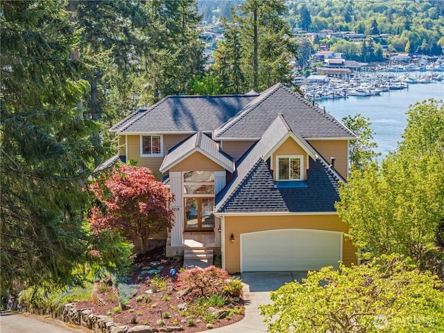 view of front of house with a water view, a shingled roof, an attached garage, and driveway
