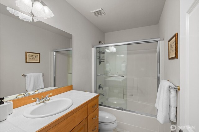 full bath featuring toilet, visible vents, shower / bath combination with glass door, and vanity