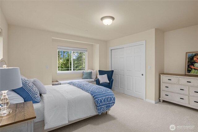 bedroom with baseboards, light colored carpet, and a closet