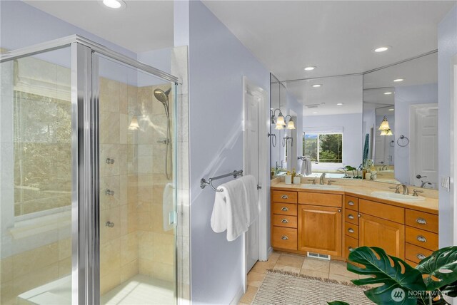 bathroom with a sink, a shower stall, and visible vents